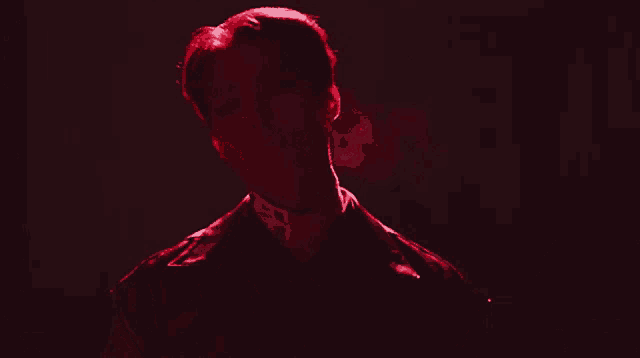a man wearing a black leather jacket is standing in a dark room