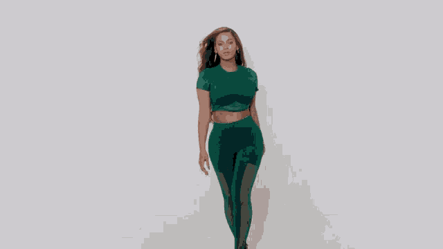 the woman is wearing a green crop top and leggings .