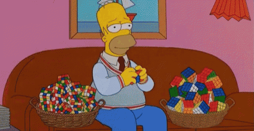 homer simpson is sitting on a couch with a basket of rubik 's cubes