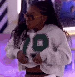 a woman wearing a white sweatshirt with the number 19 on it is taking off her shirt .