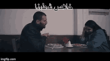 a man and a woman are sitting at a table with plates of food on it .