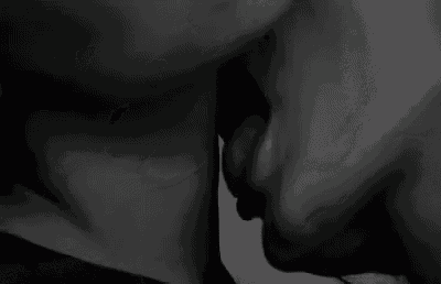 it is a black and white photo of a man and woman kissing .