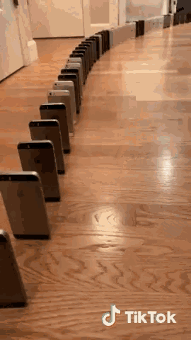 a row of iphones are lined up in a row on a wooden floor with tiktok written on the bottom
