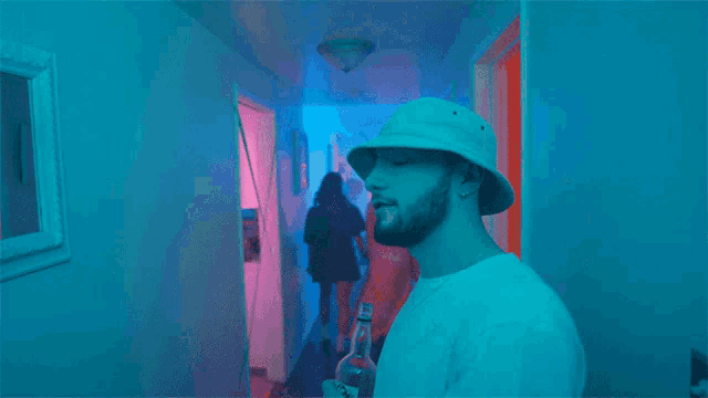 a man wearing a white hat is holding a bottle