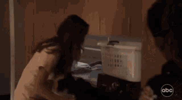 a woman is kneeling down in front of a laundry basket with abc written on the bottom right corner