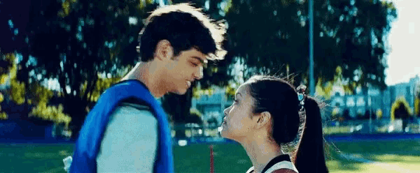a man and woman are kissing in a park .