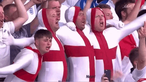 a group of men wearing white and red outfits with a cross on them are standing in a crowd .