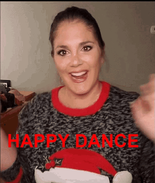 a woman wearing a christmas sweater that says happy dance