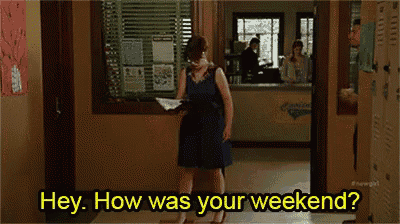 a woman in a blue dress is standing in a hallway holding a piece of paper and asking how was your weekend .