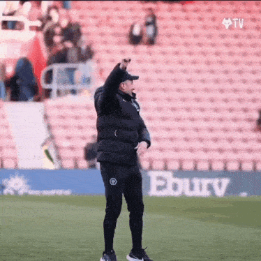 a man stands on a soccer field with his fist in the air
