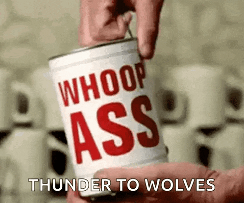 a person is holding a can of whoop ass thunder to wolves .