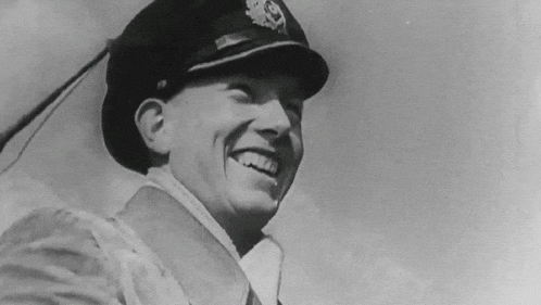 a black and white photo of a man in a hat laughing