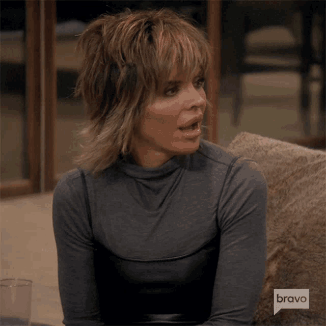 a woman sitting on a couch with a bravo logo on the corner