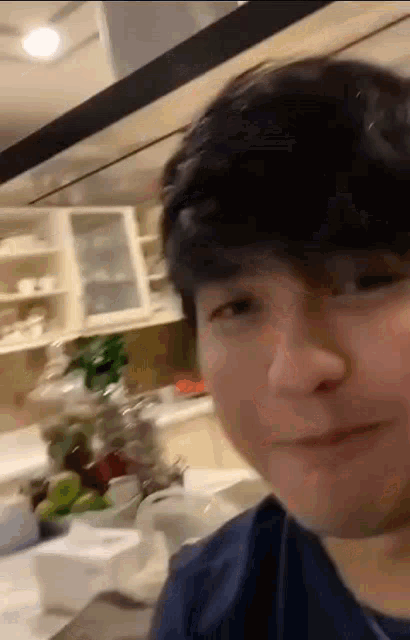 a young man is making a funny face while standing in a kitchen .