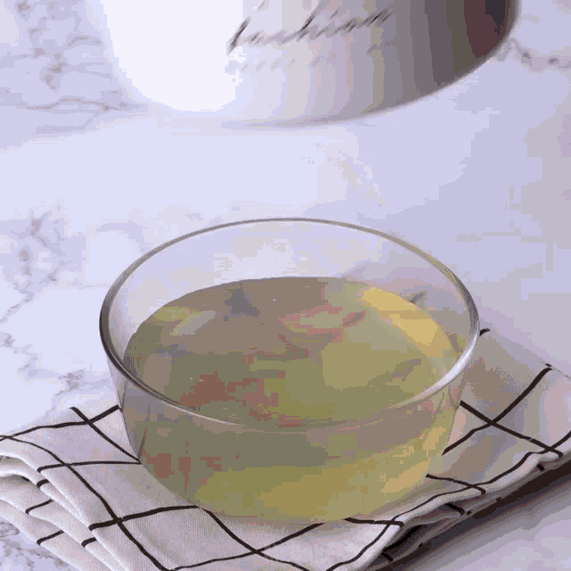a bowl of liquid is sitting on a checkered napkin