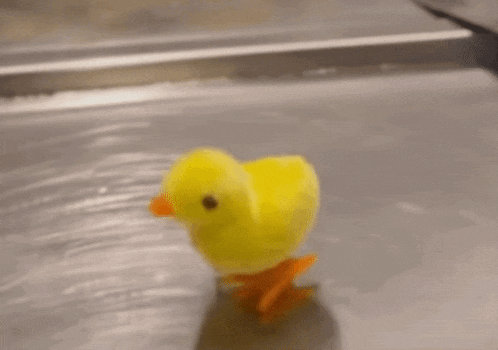 a small yellow toy chicken is walking on a counter