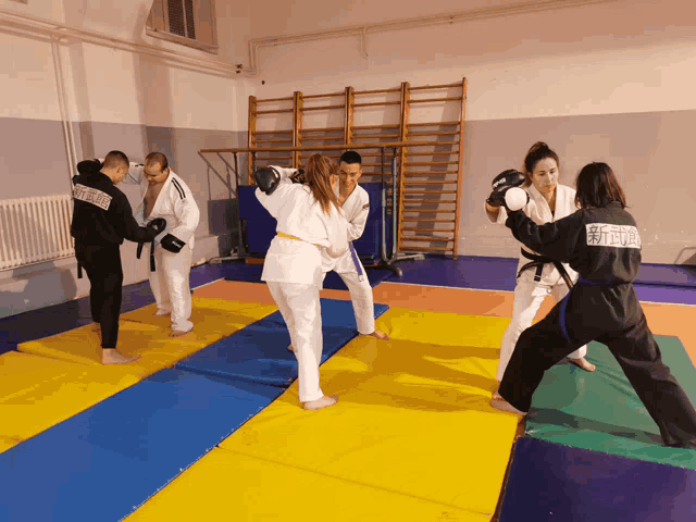 a group of people are practicing martial arts in a gym and one of them is wearing a black hoodie with the word fighter on it