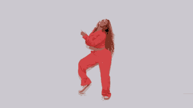 a woman in a red suit is standing in front of a white wall and dancing .