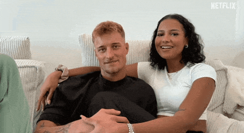 a man and a woman are sitting on a couch with a netflix logo in the corner