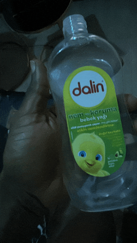 a person is holding a bottle of dalin nem koruma bebek yaği