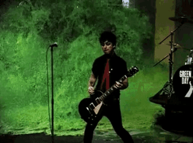 a man is playing a guitar and singing into a microphone while standing on a stage .