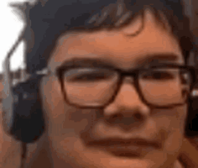 a young man wearing glasses and headphones is smiling .