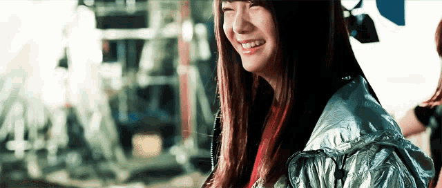 a woman wearing a silver jacket is smiling