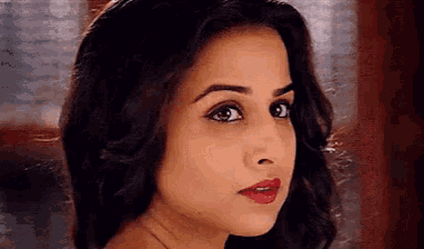 a close up of a woman 's face with red lipstick and a serious look on her face .