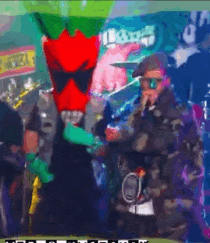 a man wearing sunglasses and a red mask stands next to a man wearing a microphone