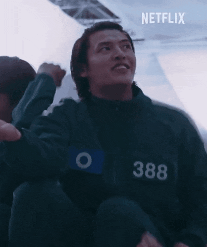 a man wearing a black jacket with the number 388 on it is sitting on a boat .