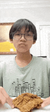 a boy wearing glasses is holding a piece of fried chicken in his hands