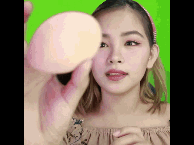 a woman holding a pink sponge in front of her face