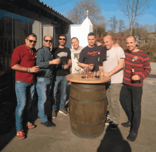 a group of men standing around a barrel with one wearing a shirt that says ' pepe jeans '