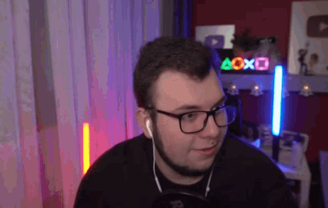 a man wearing glasses and ear buds in front of a sign that says aoxo