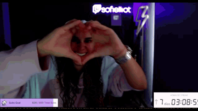 a woman is making a heart shape with her hands in front of a sign that says sofelllot