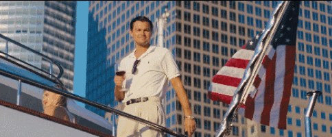 a man on a boat holding a glass of wine in front of an american flag