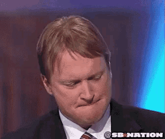 a man in a suit and tie making a funny face with a sb nation logo in the background