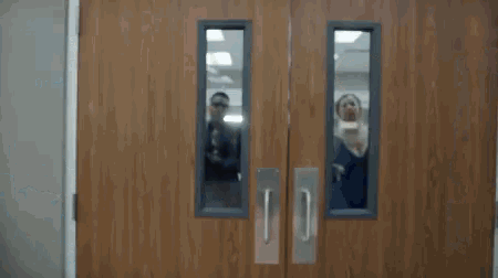 a group of people are standing behind a pair of doors