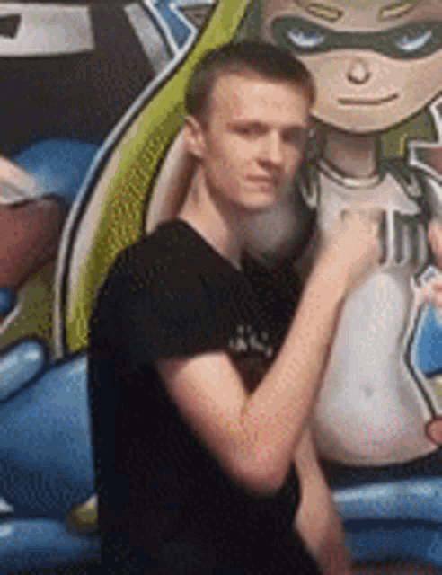 a young man is standing in front of a painting of a superhero .