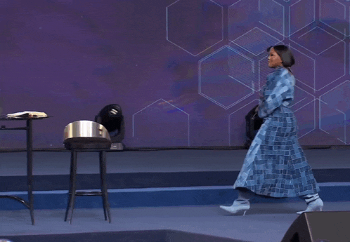 a woman in a blue dress and white boots walks on stage