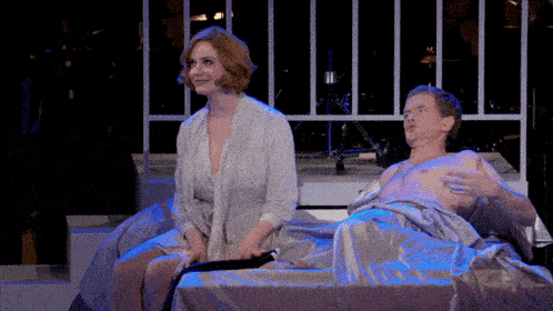 a man and a woman are sitting on a bed