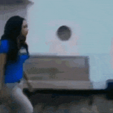 a woman in a blue shirt is standing in front of a wall
