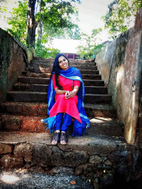 a woman in a red and blue dress sits on a set of stone steps