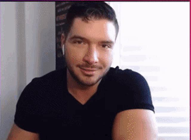 a man wearing headphones and a black shirt is smiling