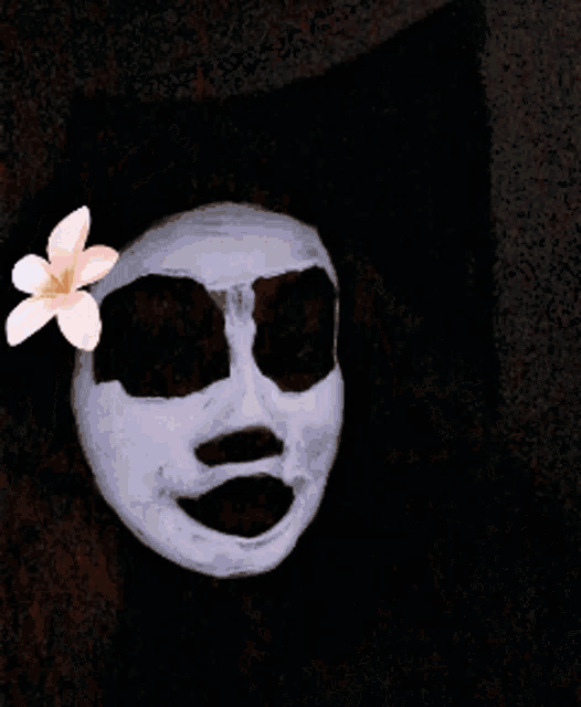 a woman wearing a blue face mask with a pink flower in her hair