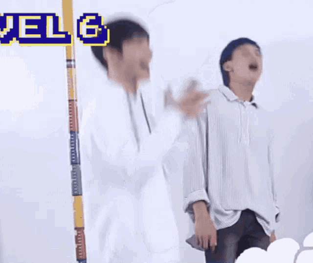 two young men are standing next to each other and one of them is standing next to a pole .