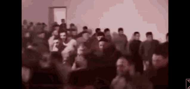 a large group of people are standing in a room in a blurry photo .