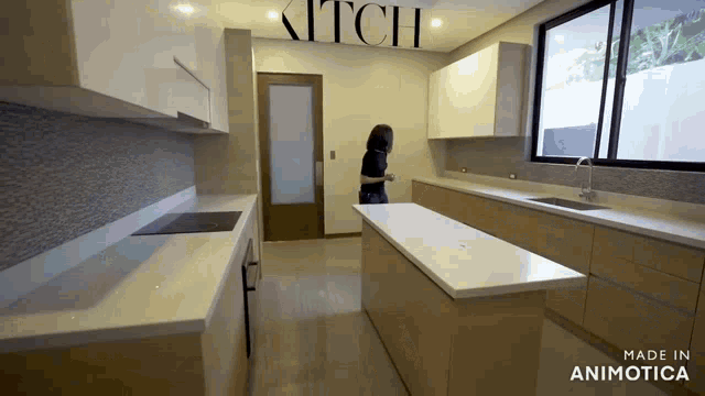 a woman is standing in a kitchen with a sign that says kitch