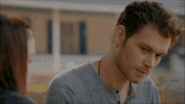 a man in a grey shirt is looking at a woman in a black shirt .