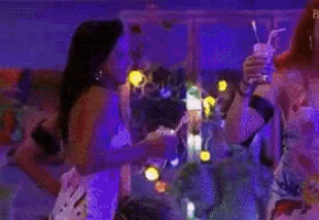 two women are drinking from straws at a party while dancing .